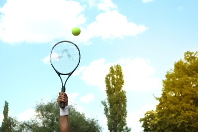 Sportsman playing tennis outdoors on sunny day, closeup
