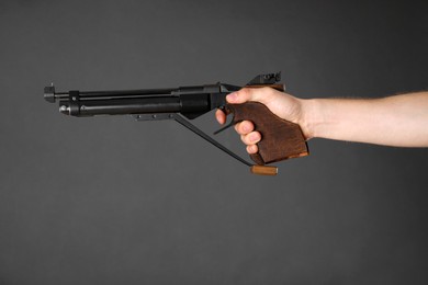 Gun shooting sport. Man aiming standard pistol on dark background, closeup