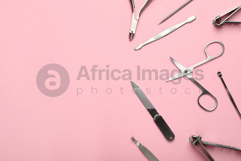 Set of manicure tools on pink background, flat lay. Space for text