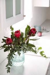 Photo of Bouquet with beautiful protea flowers on countertop in kitchen. Interior design