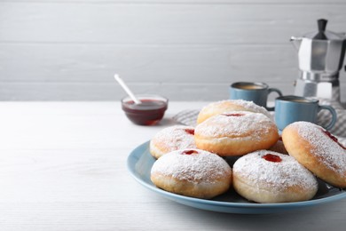 Delicious donuts with jam and powdered sugar on white wooden table. Space for text