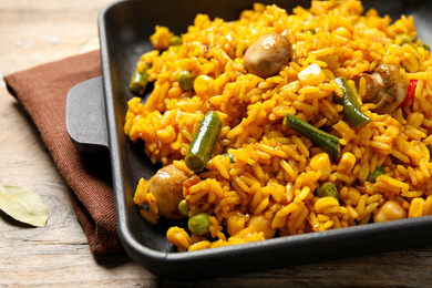 Delicious rice pilaf with vegetables on wooden table, closeup