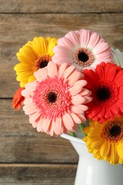 Bouquet of beautiful colorful gerbera flowers in vase on wooden background