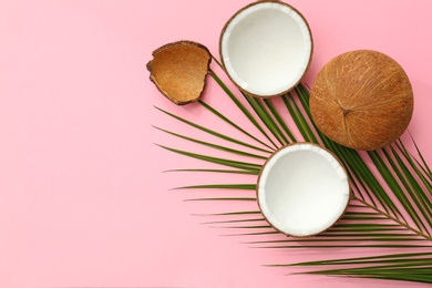 Fresh coconuts and palm leaf on pink background, flat lay. Space for text