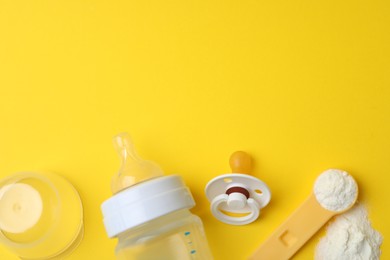Flat lay composition with powdered infant formula on yellow background, space for text. Baby milk