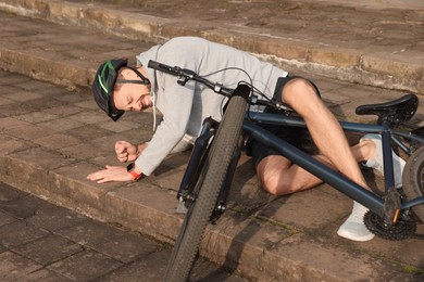 Man fallen off his bicycle on steps outdoors
