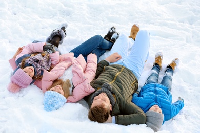 Photo of Happy family lying on snow in winter day