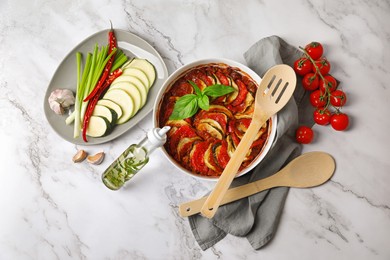 Photo of Delicious ratatouille and ingredients on white marble table, flat lay