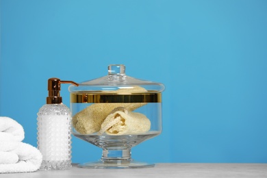Composition of glass jar with luffa sponges on table near pink wall. Space for text
