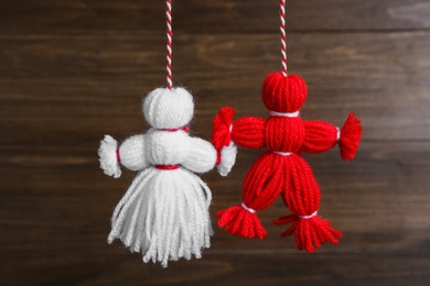Photo of Traditional martisor shaped as man and woman on wooden background. Beginning of spring celebration