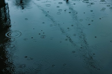 Rain drops falling down onto puddle outdoors, above view