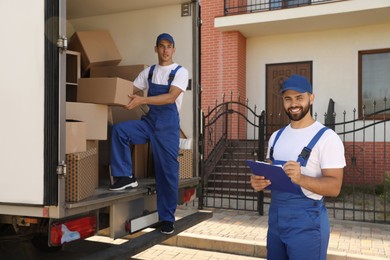 Moving service workers outdoors, unloading boxes and checking list