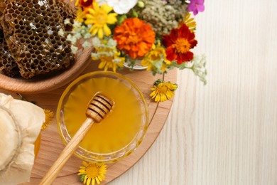 Delicious honey, combs and different flowers on wooden table, top view. Space for text