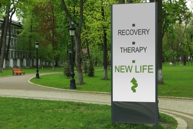 Start to live without alcohol addiction. Advertising board with inscription RECOVERY, THERAPY AND NEW LIFE  in park