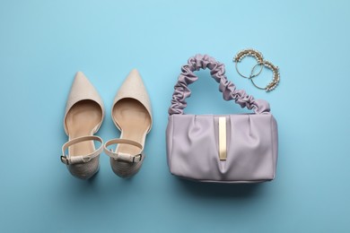 Stylish woman's bag, shoes and earrings on light blue background, flat lay