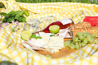Photo of Picnic blanket with delicious food and wine outdoors on sunny day