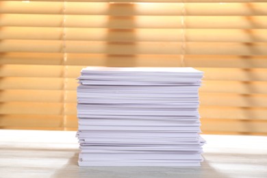 Photo of Stack of paper sheets on white wooden table