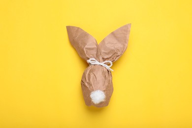 Photo of Easter bunny made of craft paper and egg on yellow background, top view