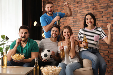 Group of friends watching football at home