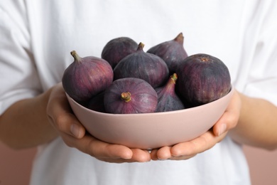 Woman holding bowl with tasty raw figs, closeup