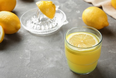 Glass with fresh lemon juice and fruits on table