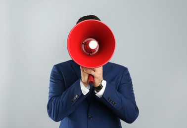 Man in suit with megaphone on grey background