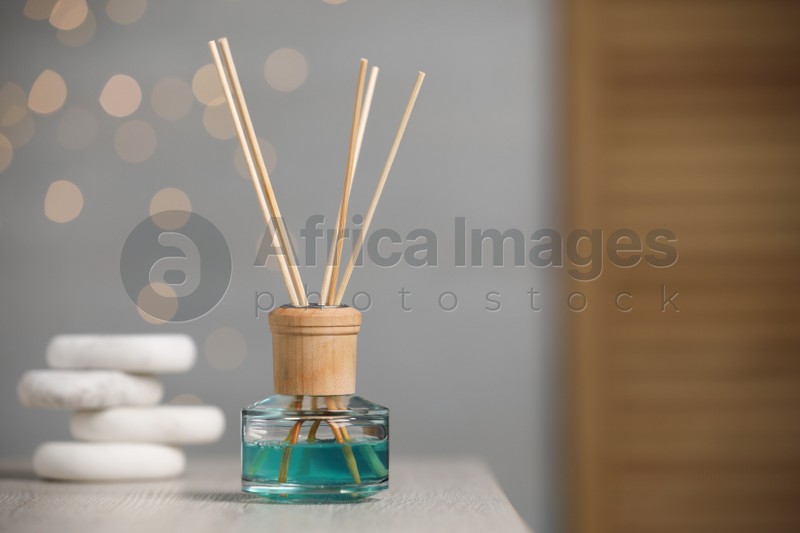 Aromatic reed air freshener and pebbles on wooden table. Space for text