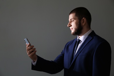Man unlocking smartphone with facial scanner on grey background. Biometric verification