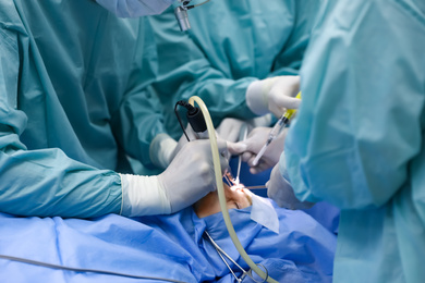 Professional doctors performing 
frontal sinus trephination in surgery room, closeup
