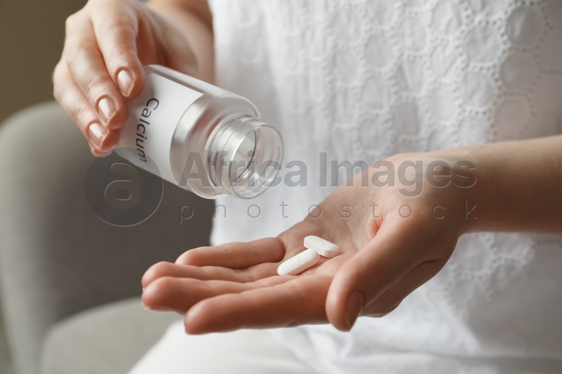 Calcium supplement. Woman taking pills indoors, closeup