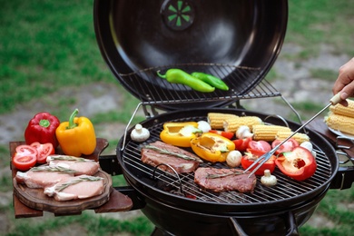Man cooking food on barbecue grill outdoors, closeup