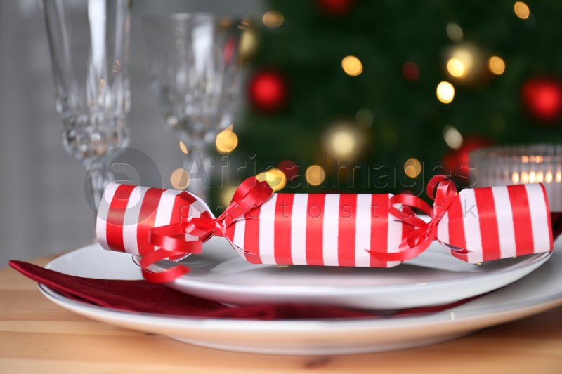 White plate with Christmas cracker on wooden table, closeup