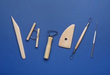 Photo of Set of clay modeling tools on blue background, flat lay