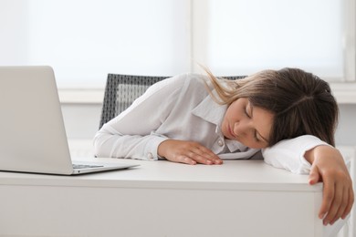 Photo of Tired young woman sleeping at workplace in office