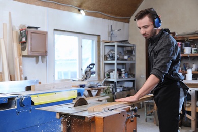 Young working man using circular saw at carpentry shop