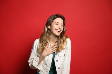 Cheerful young woman laughing on red background