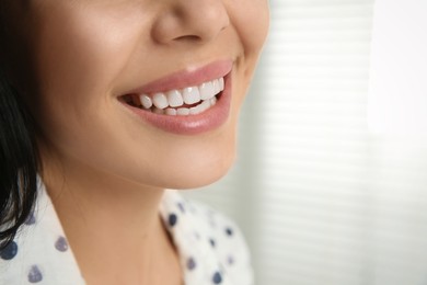 Young woman with healthy teeth on blurred background, closeup. Space for text