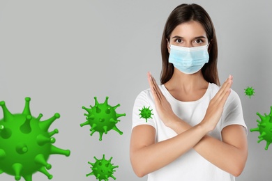 Stop Covid-19 outbreak. Woman wearing medical mask surrounded by virus on light background