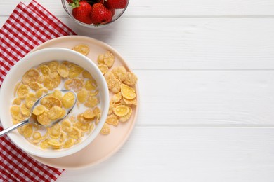 Bowl of tasty corn flakes and strawberries served on white wooden table, flat lay. Space for text
