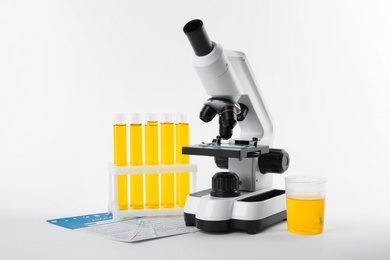 Laboratory ware with urine sample for analysis and microscope on white background