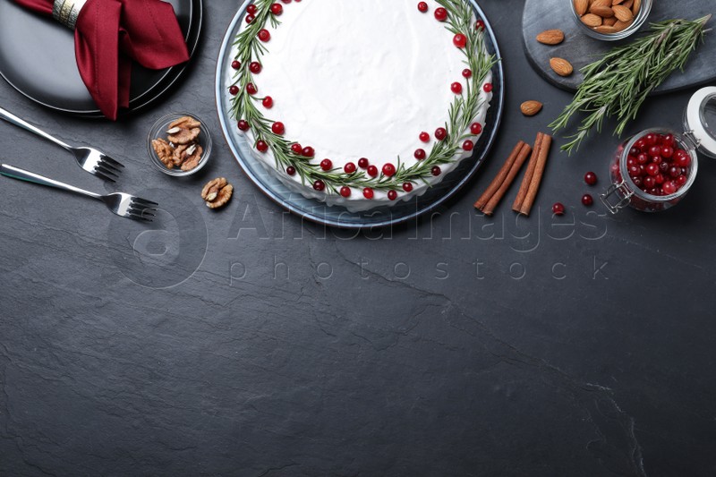 Photo of Flat lay composition with traditional Christmas cake and different ingredients on dark table, space for text