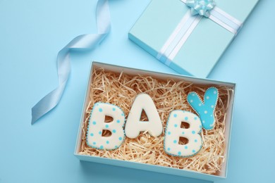 Baby shower cookies in gift box on turquoise background, flat lay