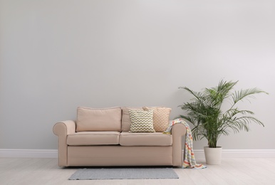 Simple room interior with comfortable beige sofa, space for text