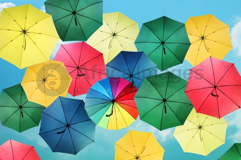 Group of different colorful umbrellas against blue sky on sunny day