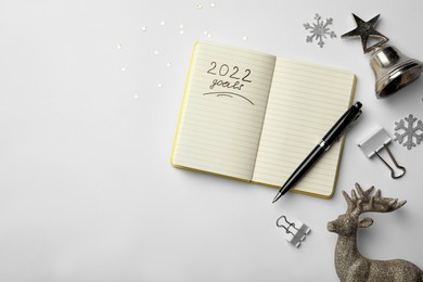 Inscription 2022 Goals written in planner and Christmas decor on white background, flat lay with space for text. New Year aims