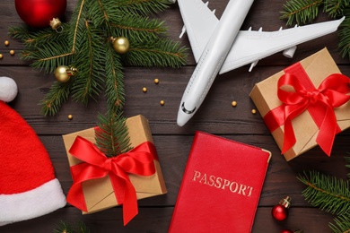Flat lay composition with Christmas decorations and toy airplane on wooden background. Winter vacation