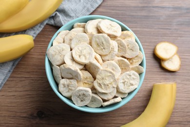 Freeze dried and fresh bananas on wooden table, flat lay