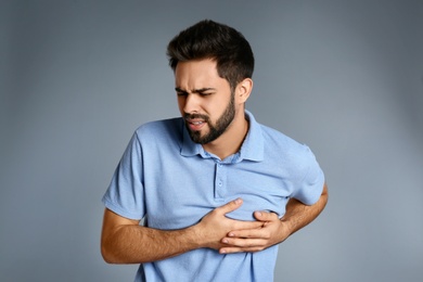 Man suffering from heart pain on grey background