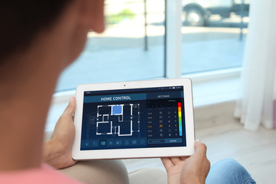 Woman using energy efficiency home control system on tablet, closeup