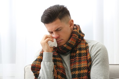 Ill man with scarf suffering from head cold at home